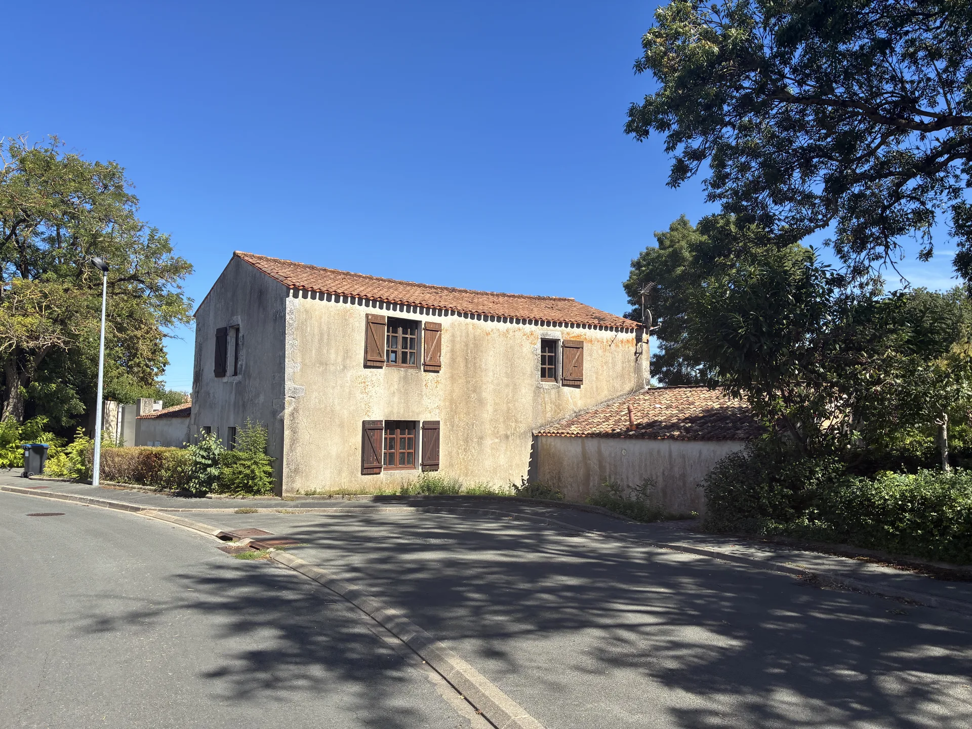 Ancienne bâtisse en pierre rue de la Source au Prieuré, La Rochelle, toit de tuiles et volets bois